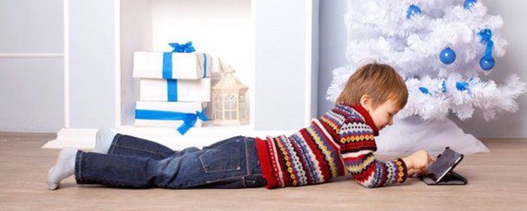 Niño viendo una película junto al árbol de Navidad